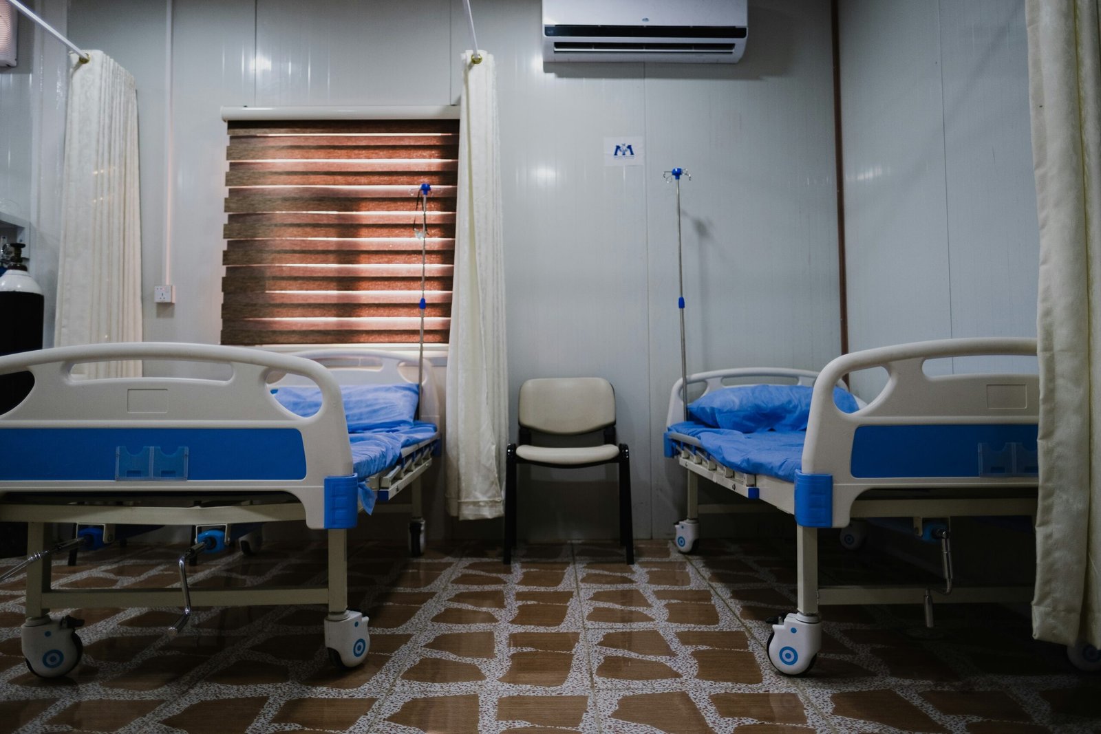 white split type air conditioner over white and blue hospital bed